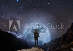 Fototapeta papr 184 x 128, 205708981 - a man with backpack standing on mountain peak at night, and silhouette mountain with bright full moon and sky full of stars