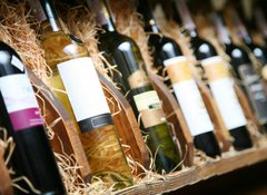 Fototapeta100 x 73  Closeup shot of wineshelf. Bottles lay over straw., 100 x 73 cm