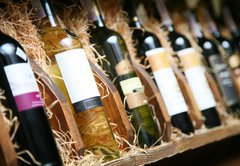 Fototapeta145 x 100  Closeup shot of wineshelf. Bottles lay over straw., 145 x 100 cm