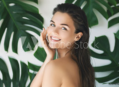 Samolepka fólie 100 x 73, 217474275 - Portrait of young and beautiful woman with perfect smooth skin in tropical leaves - Portrét mladé a krásné ženy s dokonalou hladkou pokožkou v tropických listech