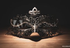 Fototapeta vliesov 145 x 100, 311256147 - A portrait of a traditional venetian mask on a wooden surface appearing mysteriously out of the darkness.