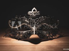 Fototapeta papr 360 x 266, 311256147 - A portrait of a traditional venetian mask on a wooden surface appearing mysteriously out of the darkness.
