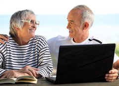 Fototapeta100 x 73  Senior couple in the garden with laptop and book, 100 x 73 cm