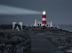 Fototapeta100 x 73  Lighthouse with shining light in darkness and dark blue clouds a, 100 x 73 cm