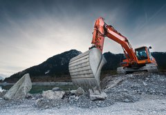 Fototapeta184 x 128  heavy organge excavator with shovel standing on hill with rocks, 184 x 128 cm