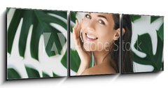 Obraz 3D třídílný - 150 x 50 cm F_BM217474275 - Portrait of young and beautiful woman with perfect smooth skin in tropical leaves - Portrét mladé a krásné ženy s dokonalou hladkou pokožkou v tropických listech