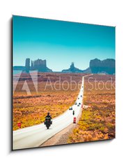 Sklenn obraz 1D - 50 x 50 cm F_F244433077 - Biker on Monument Valley road at sunset, USA - Motork na silnici Monument Valley pi zpadu slunce, USA