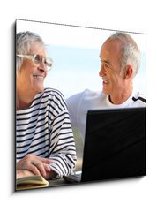Obraz 1D - 50 x 50 cm F_F46296780 - Senior couple in the garden with laptop and book - Senior pár v zahradě s notebookem a knihou