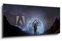 Obraz s hodinami 1D panorama - 120 x 50 cm F_AB205708981 - a man with backpack standing on mountain peak at night, and silhouette mountain with bright full moon and sky full of stars