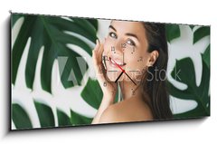 Obraz s hodinami 1D panorama - 120 x 50 cm F_AB217474275 - Portrait of young and beautiful woman with perfect smooth skin in tropical leaves - Portrét mladé a krásné ženy s dokonalou hladkou pokožkou v tropických listech