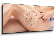 Obraz s hodinami 1D panorama - 120 x 50 cm F_AB524125512 - Beautiful slender woman sits on a couch in a spa salon. She shows varicose veins in the lower legs.Treatment of varicose veins and capillaries.